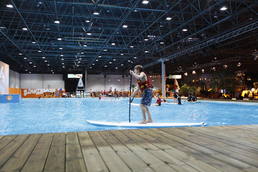 A person paddle-boarding in a large indoor pool at Boot 2011 exhibition in Düsseldorf.