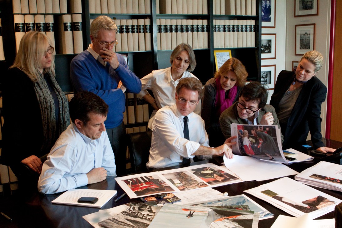 Olivier Royant and section editors review layout proofs and photographs around a conference table.