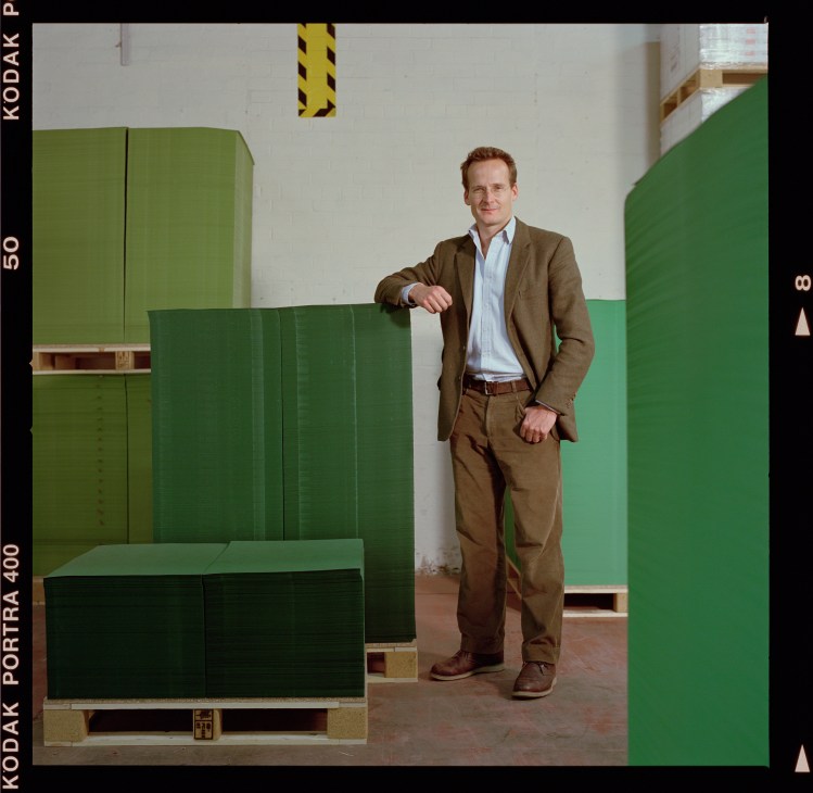 Mark Cropper, sixth-generation chairman of James Cropper paper mill, standing beside stacks of green paper rolls.