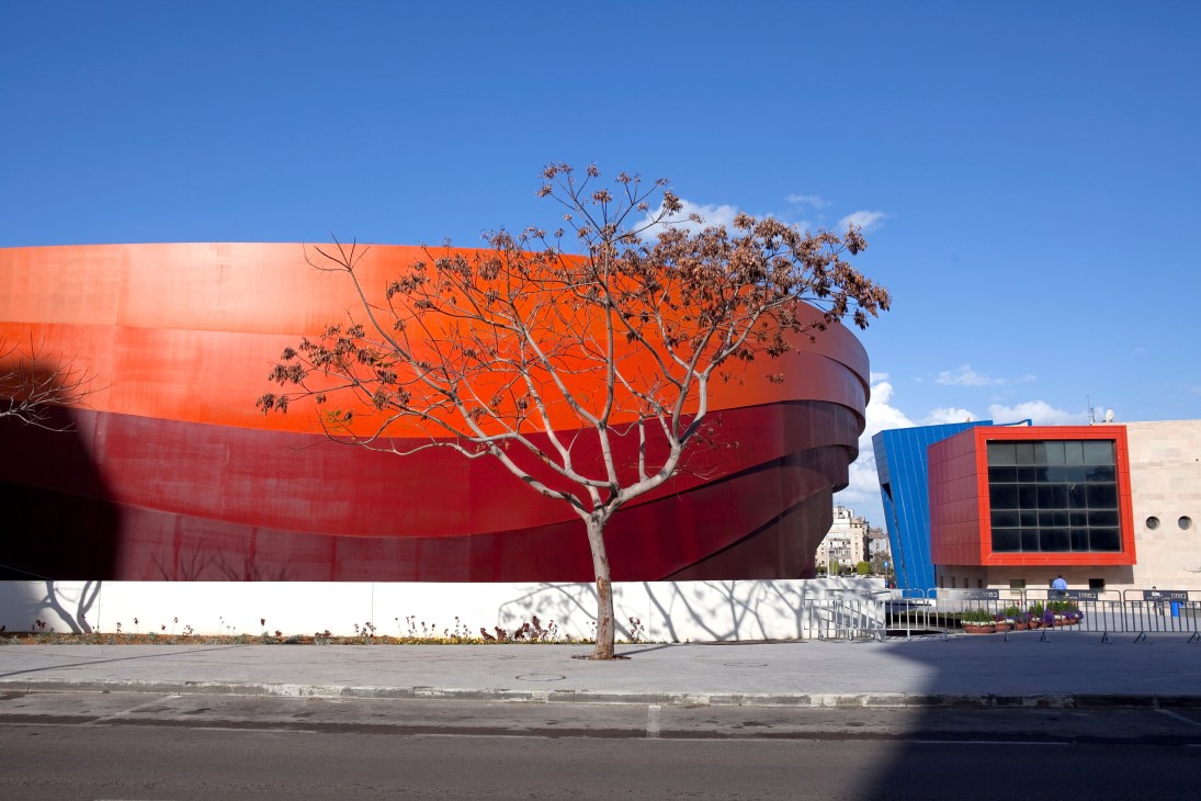 Ron Arad's Design Museum in Holon, Israel, features curved red and white metal exterior walls with a bare tree in front.