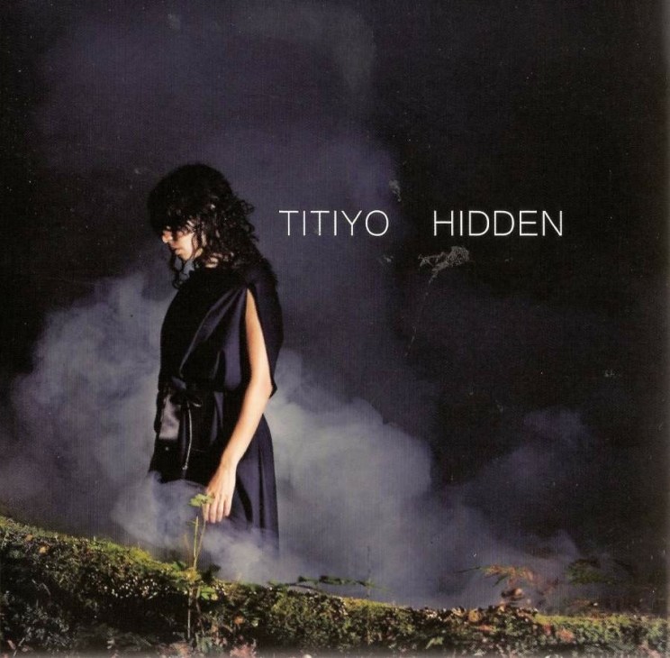 Titiyo album cover for Hidden featuring a woman in dark clothing among mist and foliage.