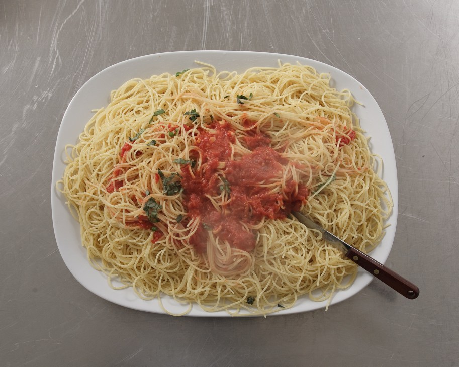 Bowl of spaghetti alla Mera with tomato sauce, basil, and a fork on white plate.