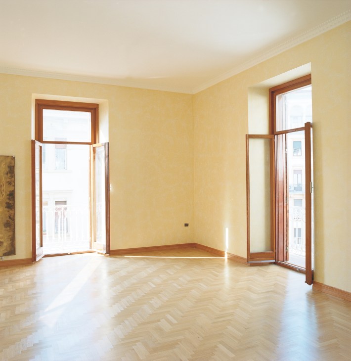 Bright yellow room with wooden doors opening to balconies in a Vomero apartment.