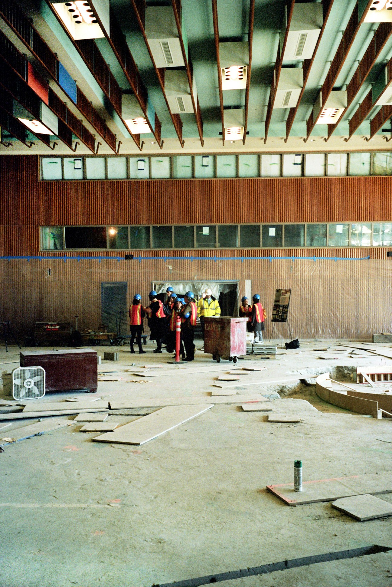 Workers in safety gear restore the Trusteeship Council Chamber with sculptural ceiling and wood paneling visible above.