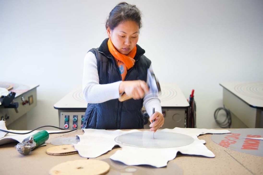An artisan cuts leather thongs from a hide at Atelier Charles Schambourg's Brussels workshop.