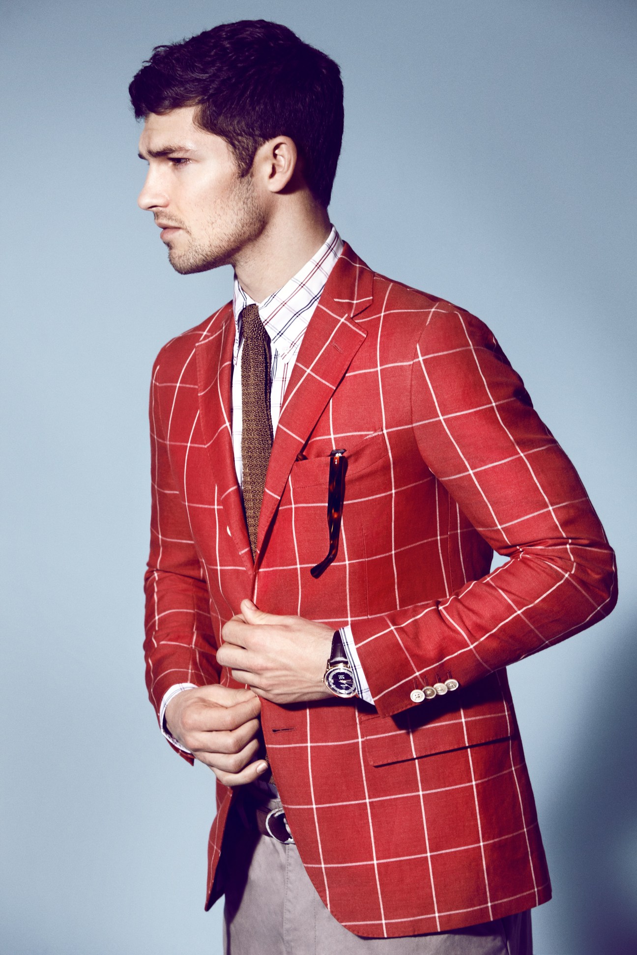 Male model wearing a red plaid Salvatore Ferragamo jacket with a striped shirt and accessories.