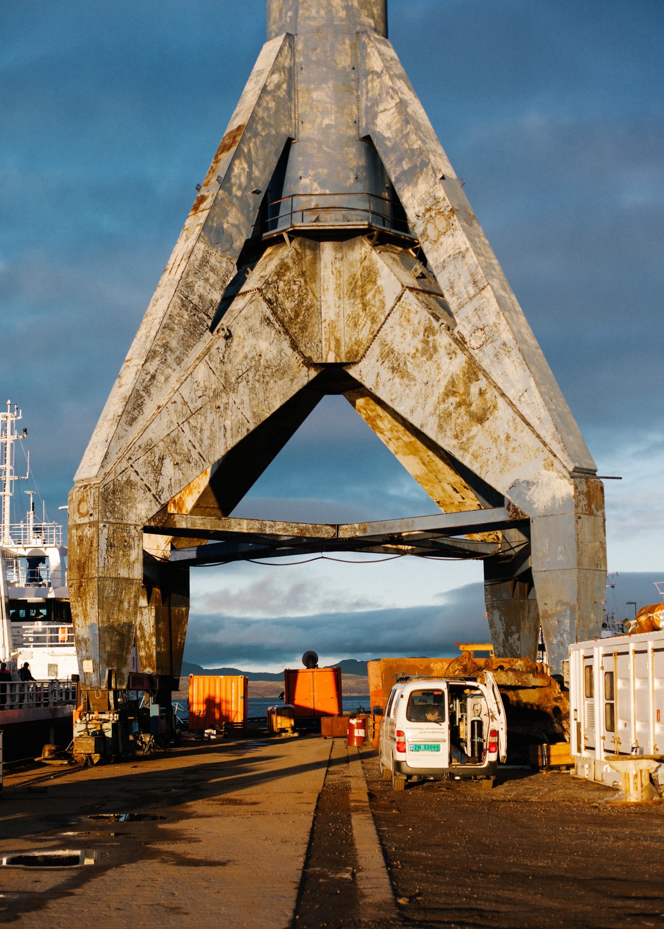 Industrial crane at Kimek shipyard dock in Kirkenes with fjord and mountains visible beyond.