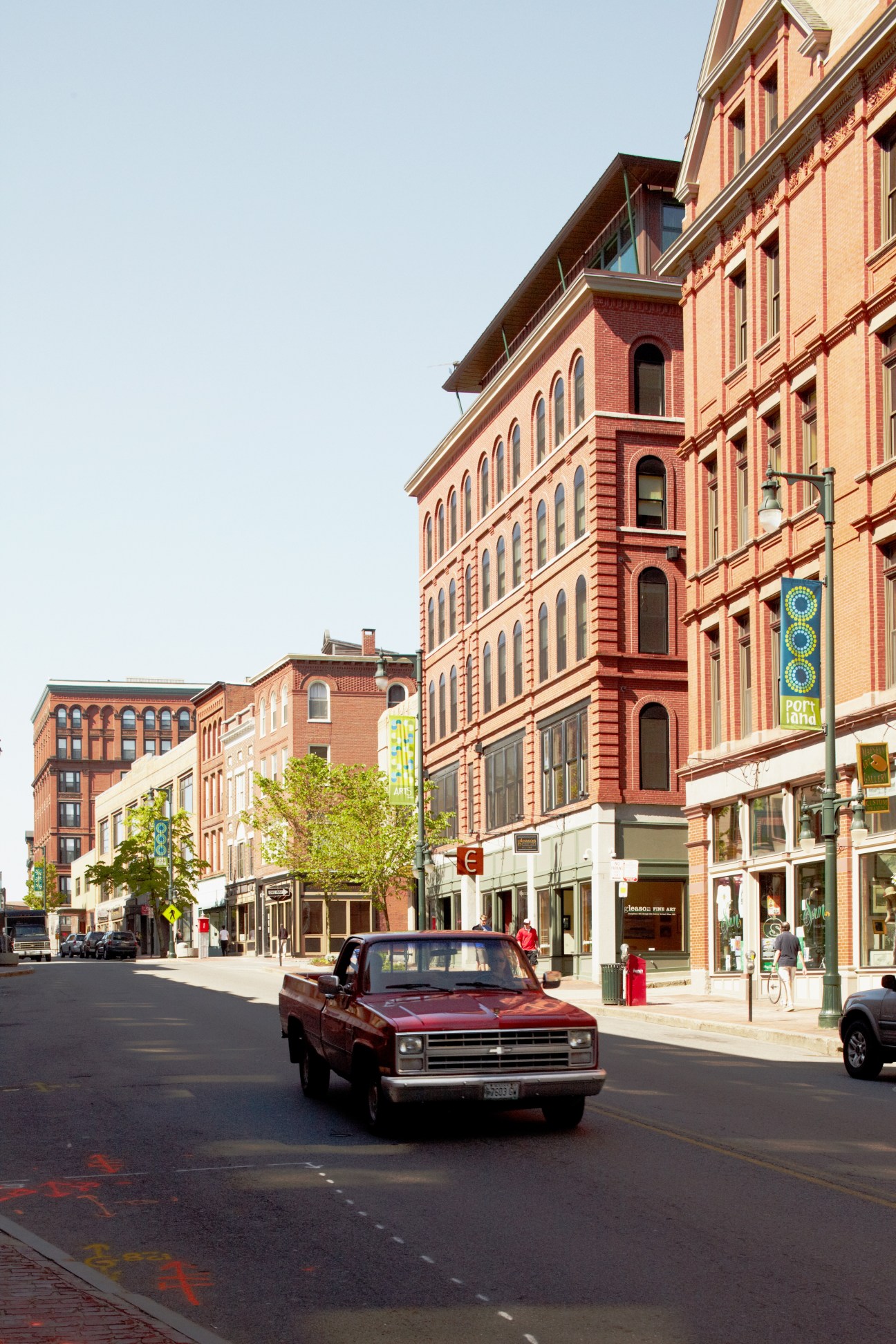 A red pickup truck drives down Congress Street past historic red-brick buildings with storefronts.
