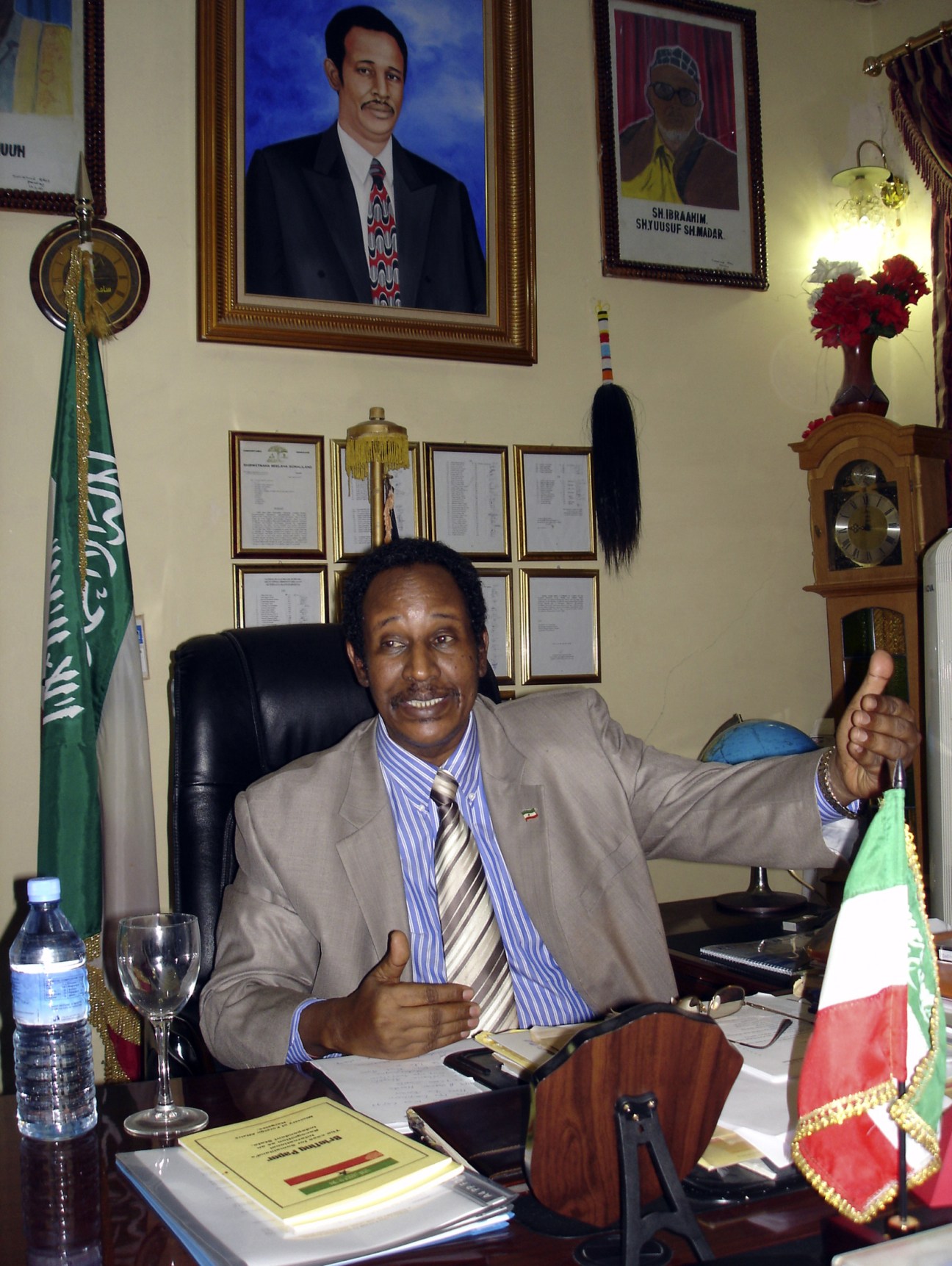 President Dahir Riyale Kahin seated at his desk in his office, smiling at the camera.