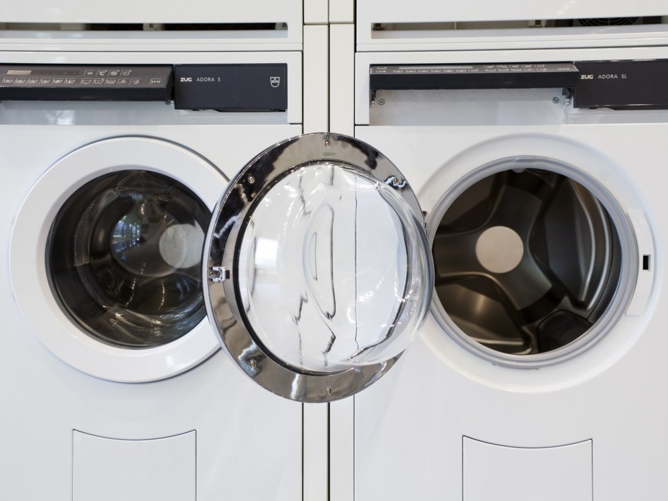 Three white V-Zug washing machines displayed in a row with open doors showing their drums.