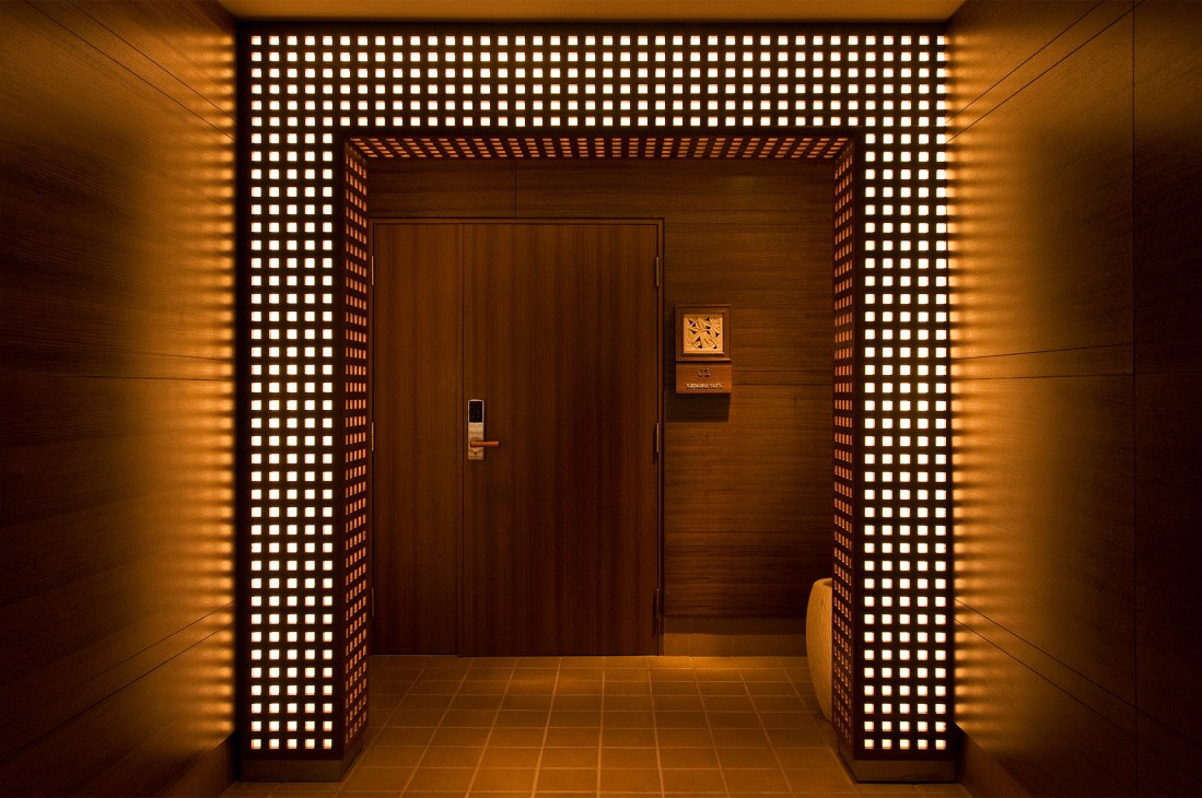 Illuminated corridor with wooden door and latticed light panels at Sankara Hotel.