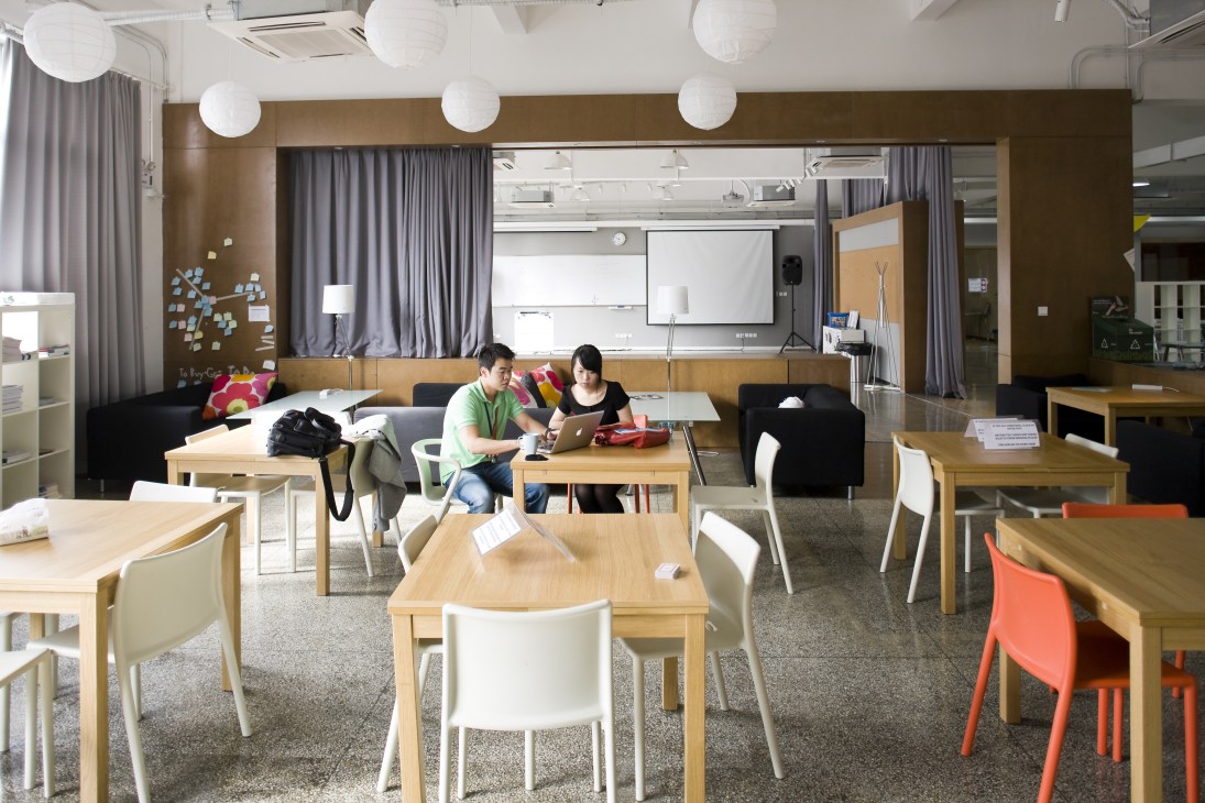 Two students work at a wooden table in a modern classroom with Finnish-designed furniture at Aalto-Tongji Design Factory in Shanghai.