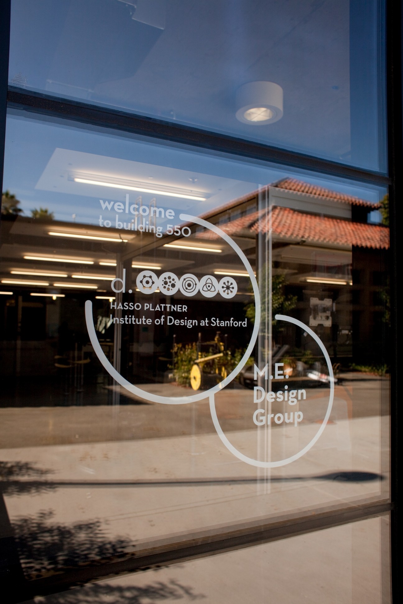Glass entrance door with white etched signage for the Hasso Plattner Institute of Design at Stanford.