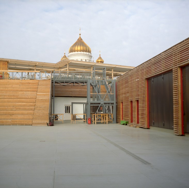Strelka Institute's wooden courtyard with Christ the Saviour Cathedral's golden dome visible behind the building.