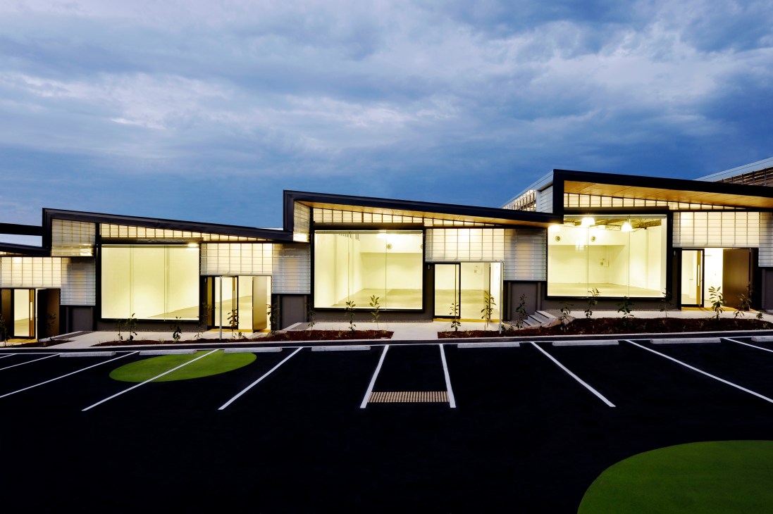 Modern retail sheds with illuminated interiors, black frames, and fibreglass cladding at Brickworks South in Brisbane.