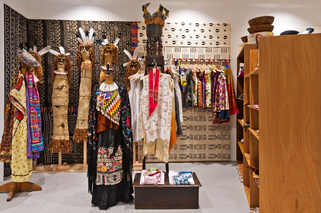 Michael Costiff's World Archive display with ornate dressed mannequins wearing colorful traditional textiles and wooden furniture pieces.