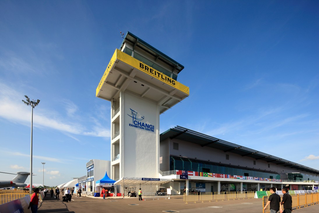 Changi Exhibition Centre exterior with tall tower featuring Breitling branding and international flags.