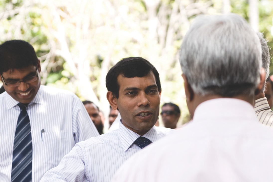 President Mohamed Nasheed in white shirt and tie speaks with an older man during a meeting with fishery managers on a tropical island.