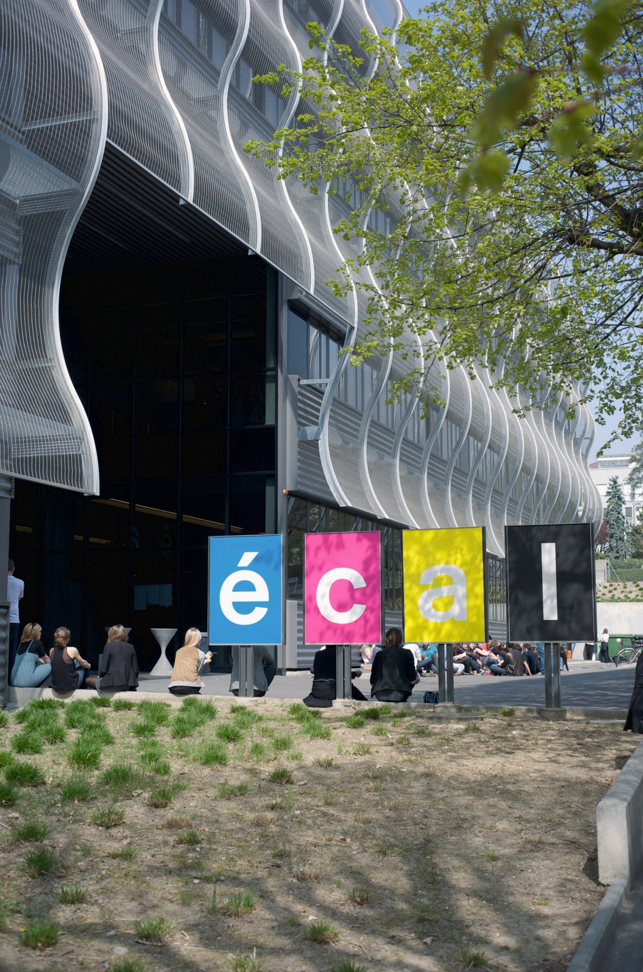 ECAL's main entrance showing the undulating metal mesh façade designed by Bernard Tschumi with colorful signage.