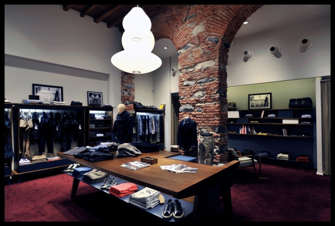 Interior of Officina Slowear store in Milan showing clothing displays and distinctive white pendant lighting.