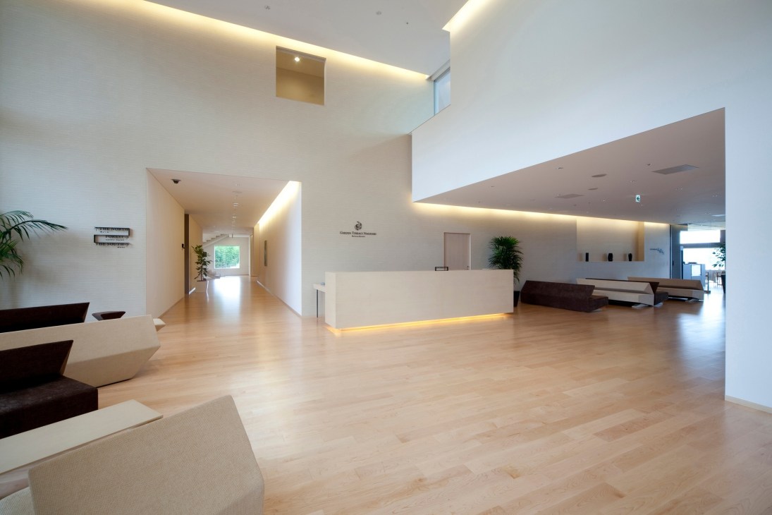 Modern minimalist spa reception area with white walls, wooden floors, and ambient lighting at Kanebo Sensai Select spa.