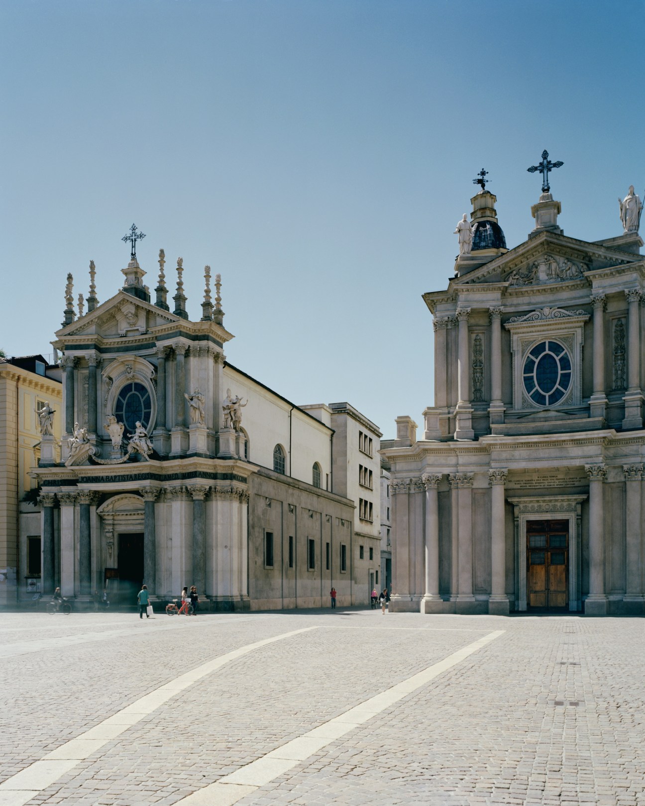 Twin baroque churches with ornate facades and crosses in Turin's central square.