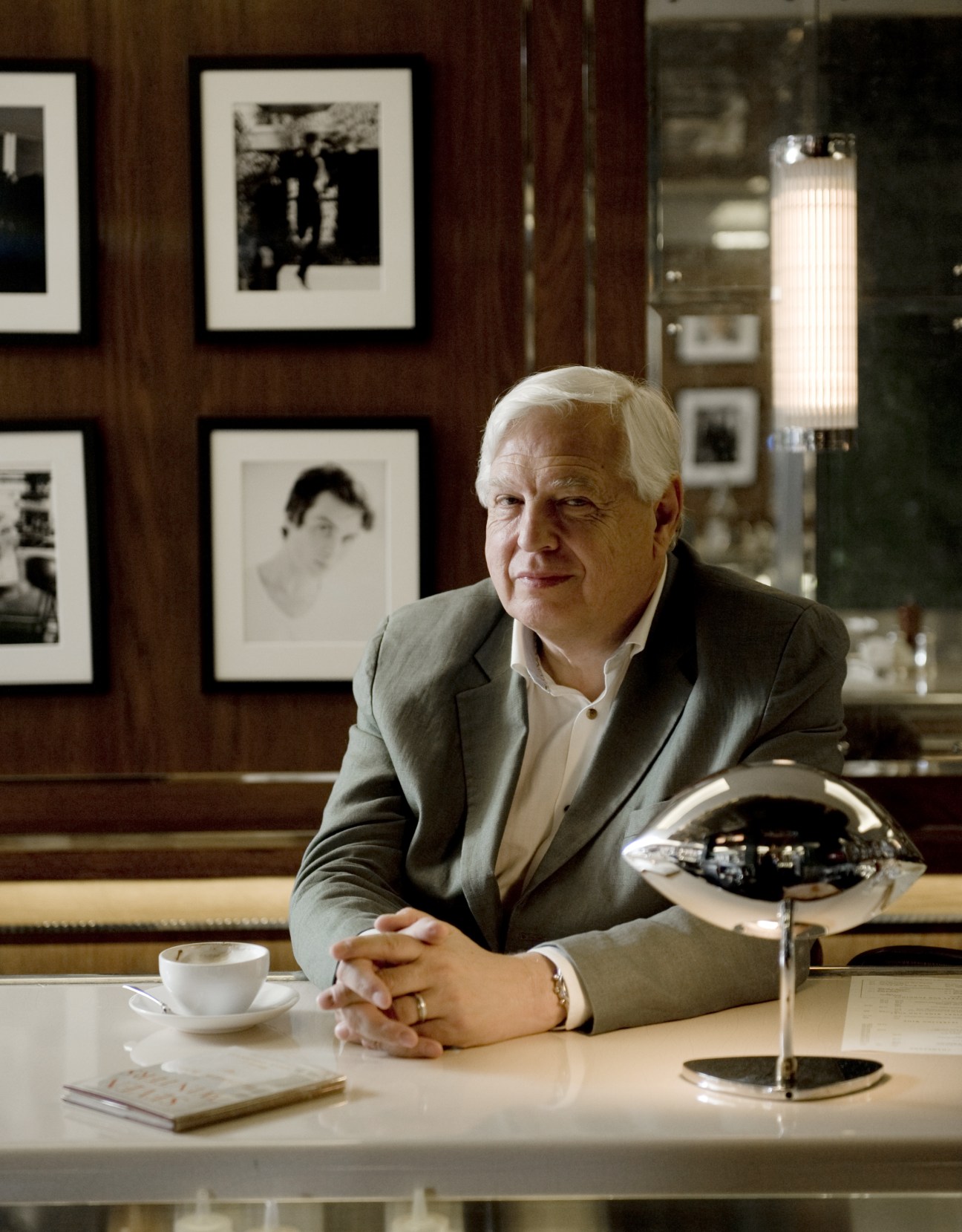 BBC world affairs editor John Simpson sits at a bar counter in J Sheekey restaurant with framed photographs behind him.