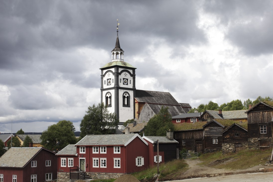 Røros town church with white and black clock tower rising above red wooden buildings.