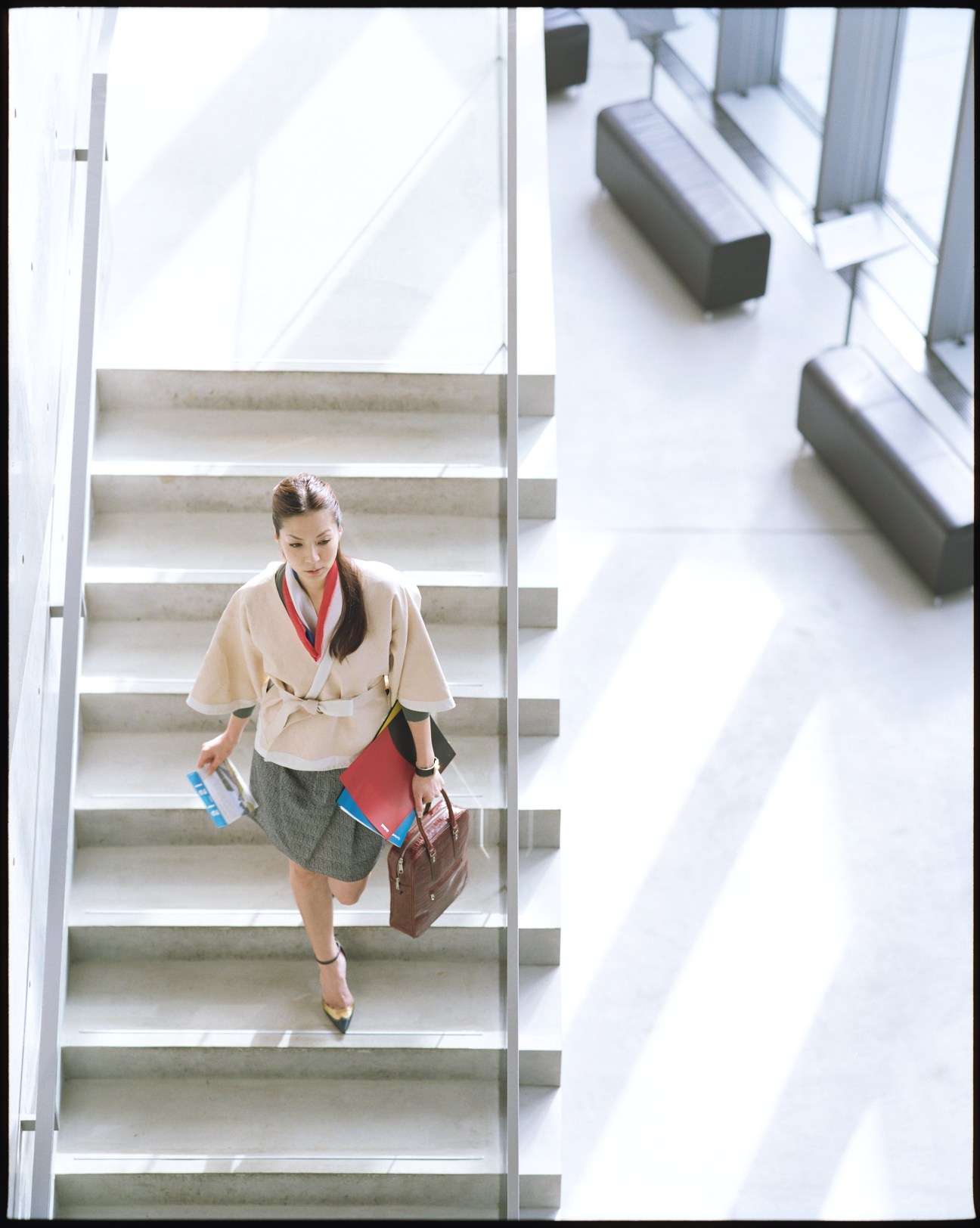 Model wearing Bottega Veneta jacket and Yves Saint Laurent cardigan descending modern staircase at 21_21 Design Sight.
