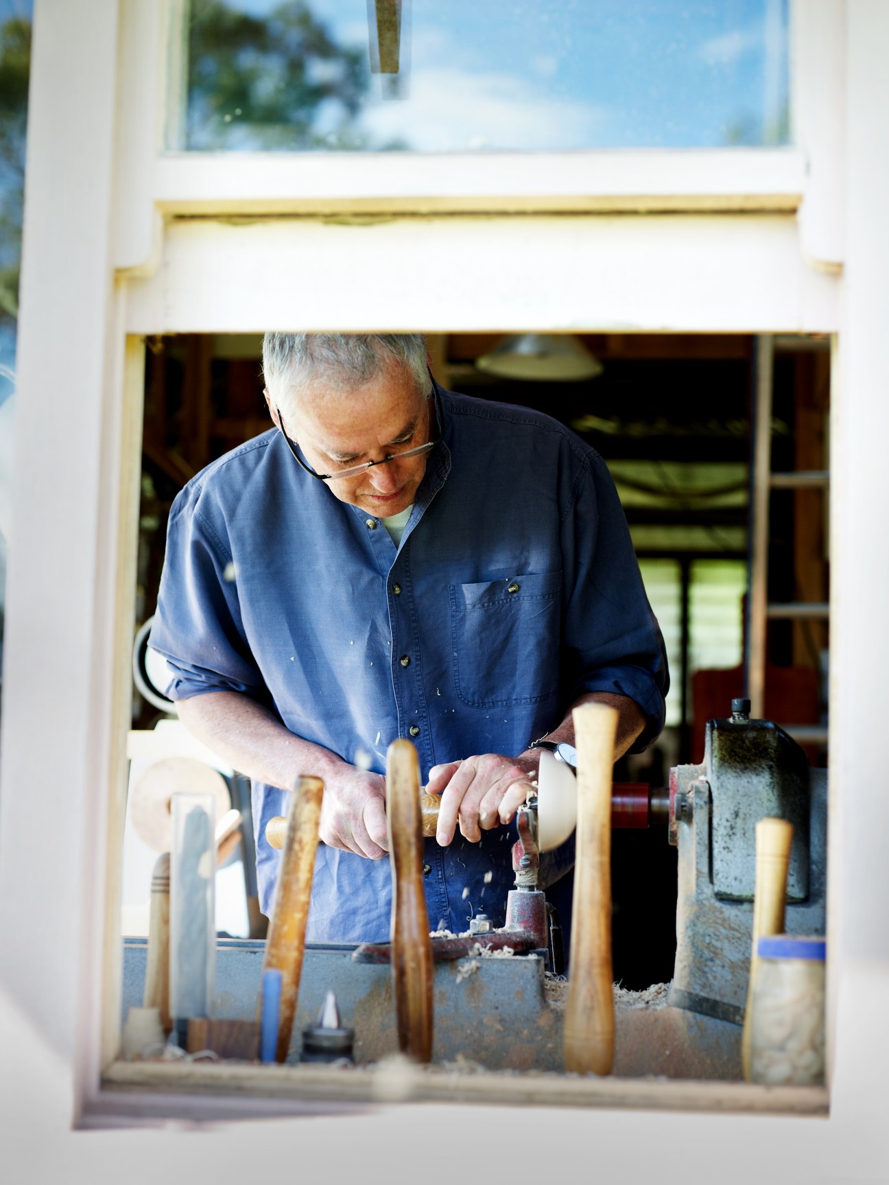Patrick Senior working at his lathe in his woodworking workshop, surrounded by wooden tools.