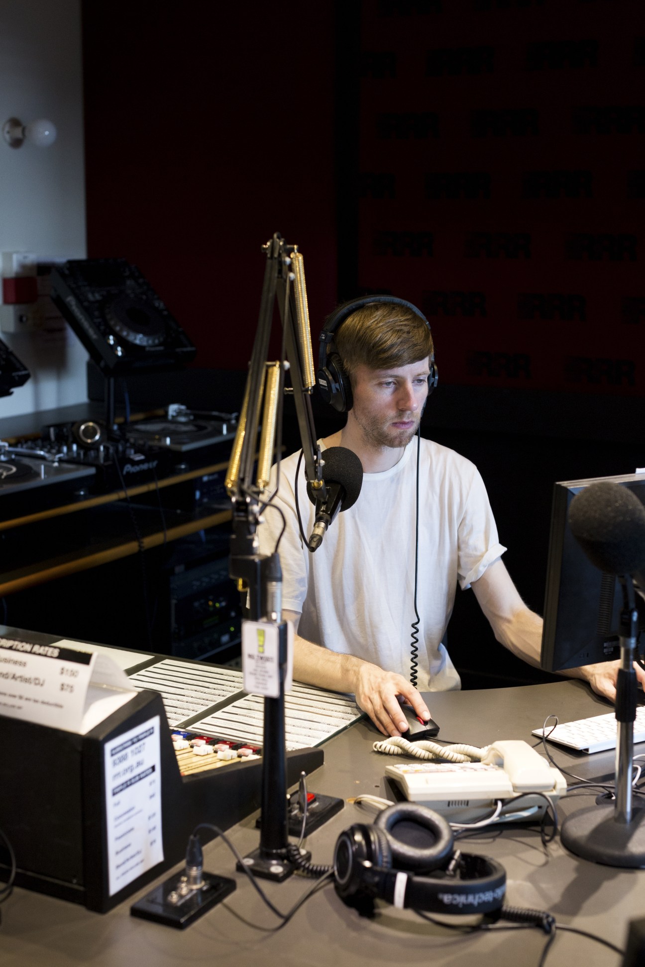 Simon Winkler wearing headphones at a microphone in Triple R's broadcasting studio.