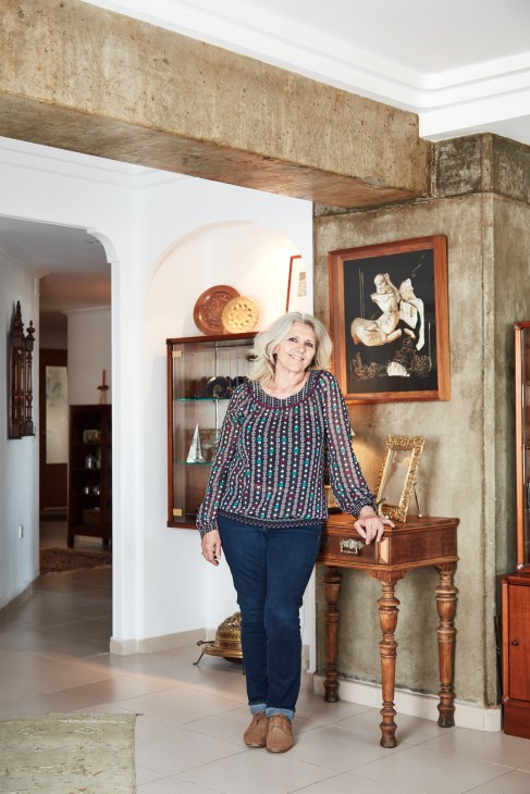 Founding resident Maite Queratt standing in her apartment at Espai Verd, next to a wooden side table.