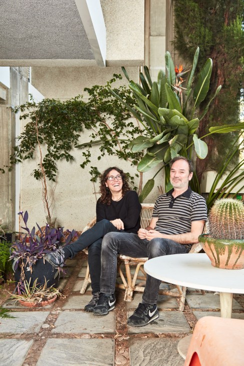 Two architects sit on a bench in a lush plant-filled courtyard at Espai Verd residential complex in Valencia.