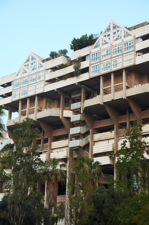 Brutalist facade of Espai Verd apartment building with stacked geometric units, vegetation, and distinctive roof design in Valencia.