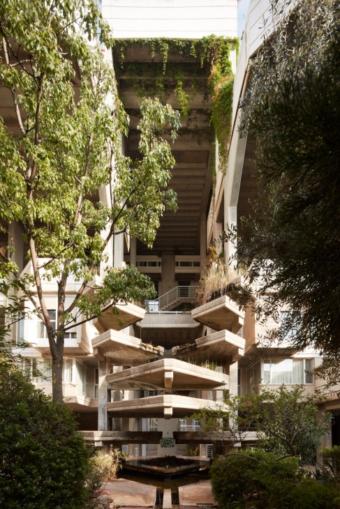 Interior courtyard of Espai Verd with cascading plants and a central fountain beneath brutalist concrete balconies.