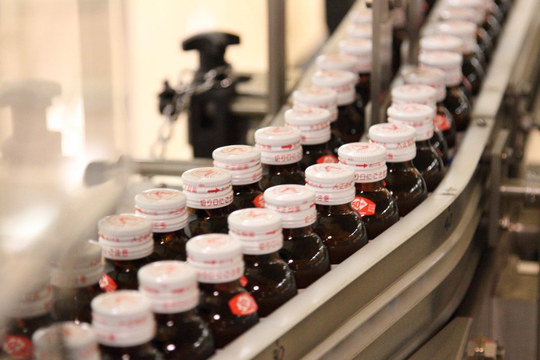 Lipovitan D bottles with white and red caps moving along a production line during manufacturing.