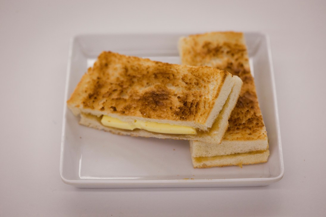Traditional butter kaya toast from Toast Box on a white plate, with cinnamon sugar topping and custard filling.