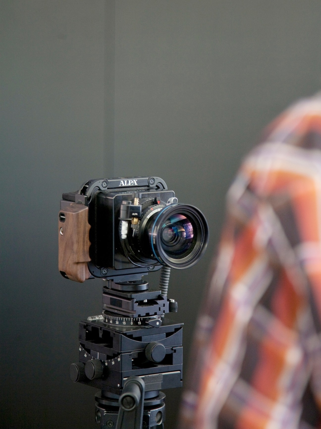 Alpa 12 medium format camera with rosewood handgrip mounted on tripod head against neutral background.