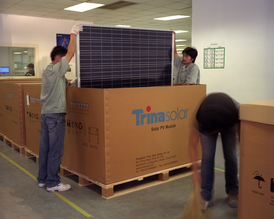 Two workers pack a Trina Solar photovoltaic module into a cardboard shipping box at the Changzhou facility.