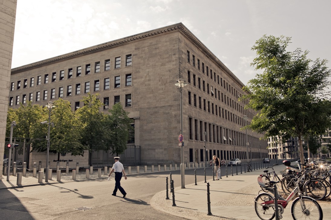 Exterior of the Federal Foreign Office building in Berlin, a large stone structure with regular window patterns and modern security barriers.