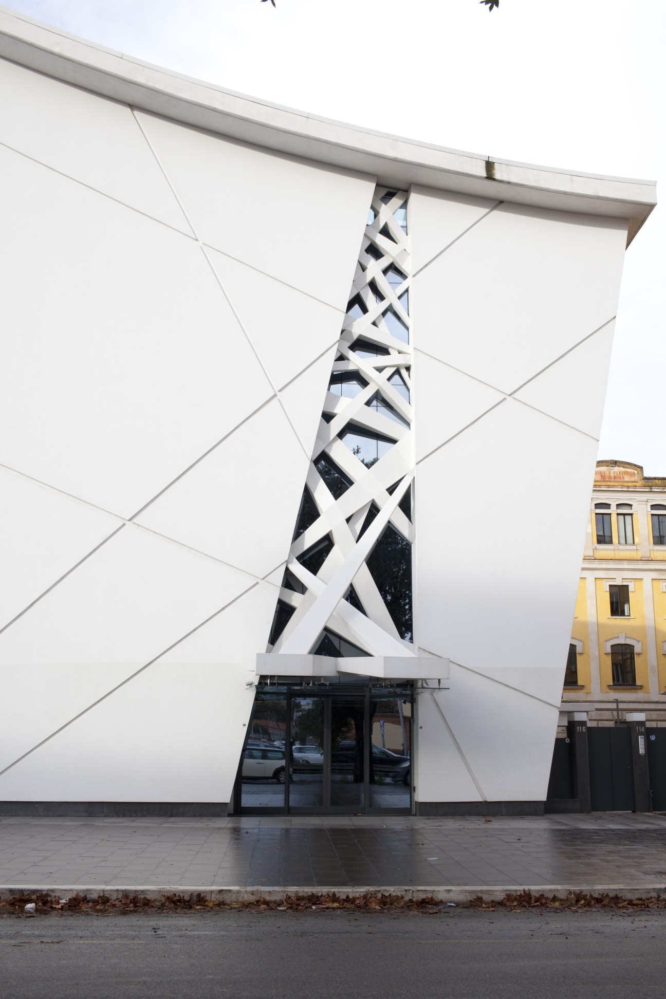 Modern white office building with geometric lattice pattern on via Ostiense, Rome.