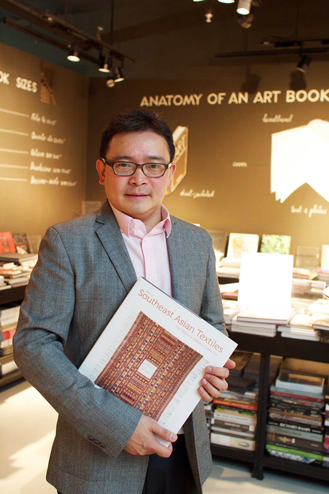 Shane Suvikapakornkul holds a Southeast Asian textiles book in Hardcover bookshop, Bangkok.