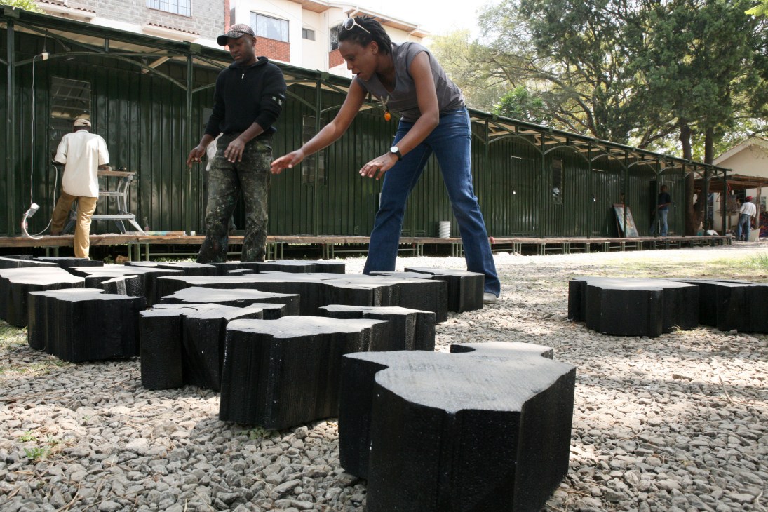Kenyan artist Ato Abe works on an interactive wooden map installation of Africa with wooden country-shaped pieces.