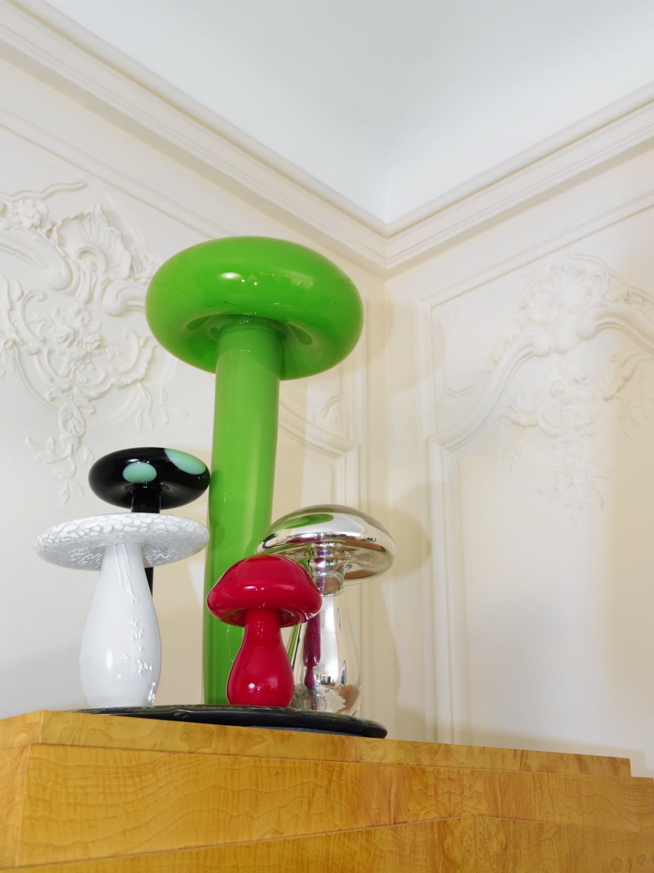 Rob Wynne's Big Green No. 8, a sculptural artwork featuring colorful mushroom-shaped objects on a tall green stem against ornate white molding.