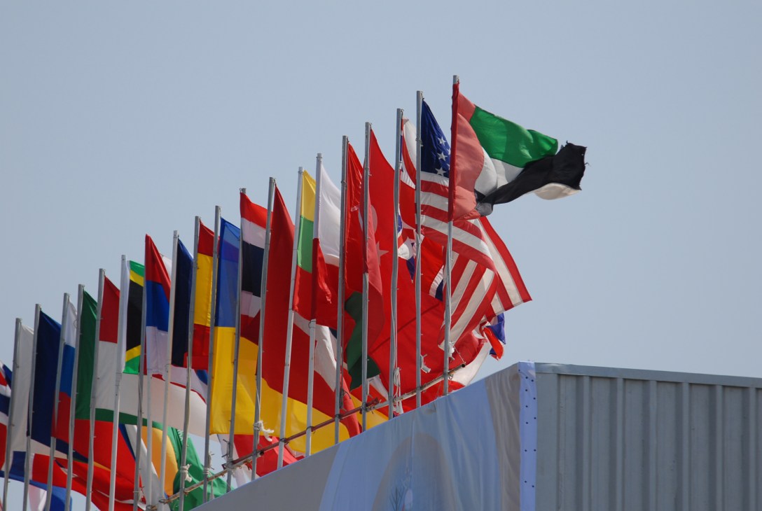Multiple international flags flying on poles at the IDEX defence exhibition in Abu Dhabi.