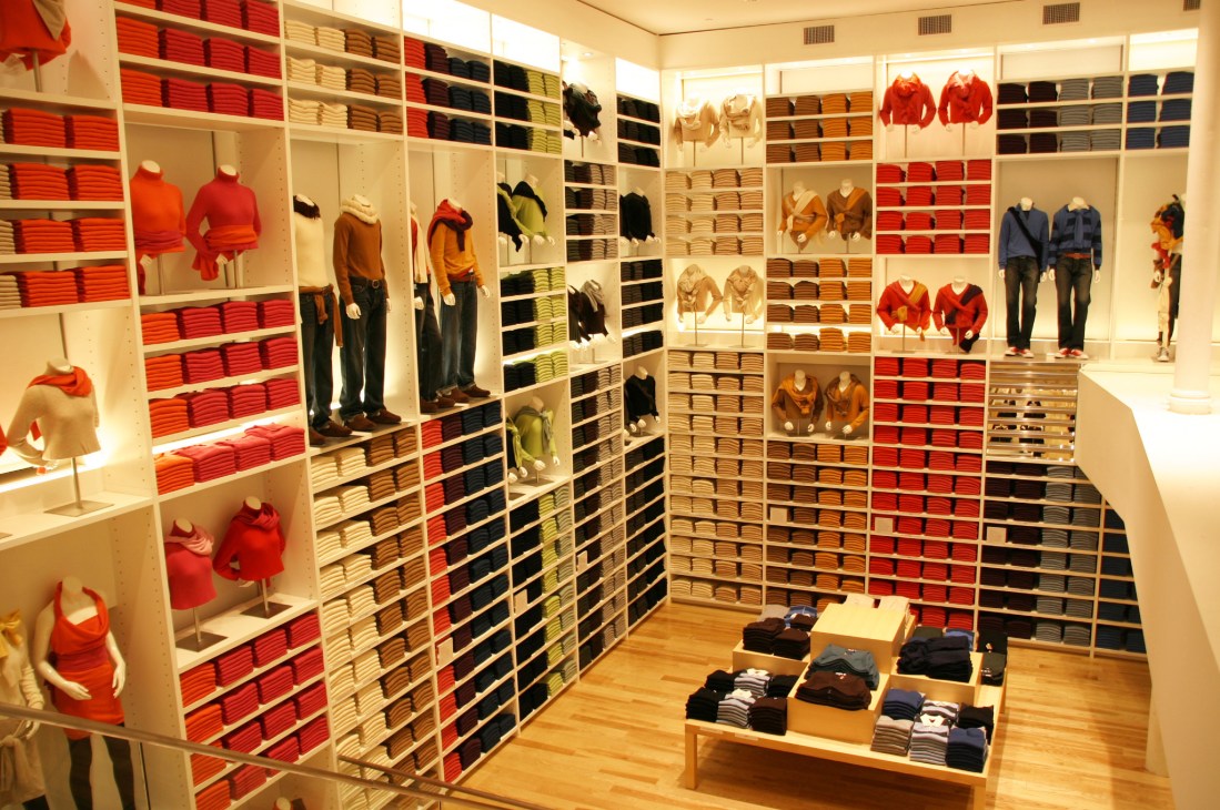 Uniqlo store interior in SoHo, New York, displaying folded clothing in organized shelving with mannequins wearing red and neutral-toned outfits.