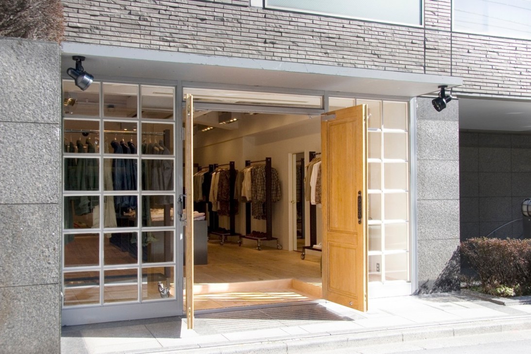 Engineered Garments flagship store exterior with gridded windows and wooden door entrance in Tokyo.