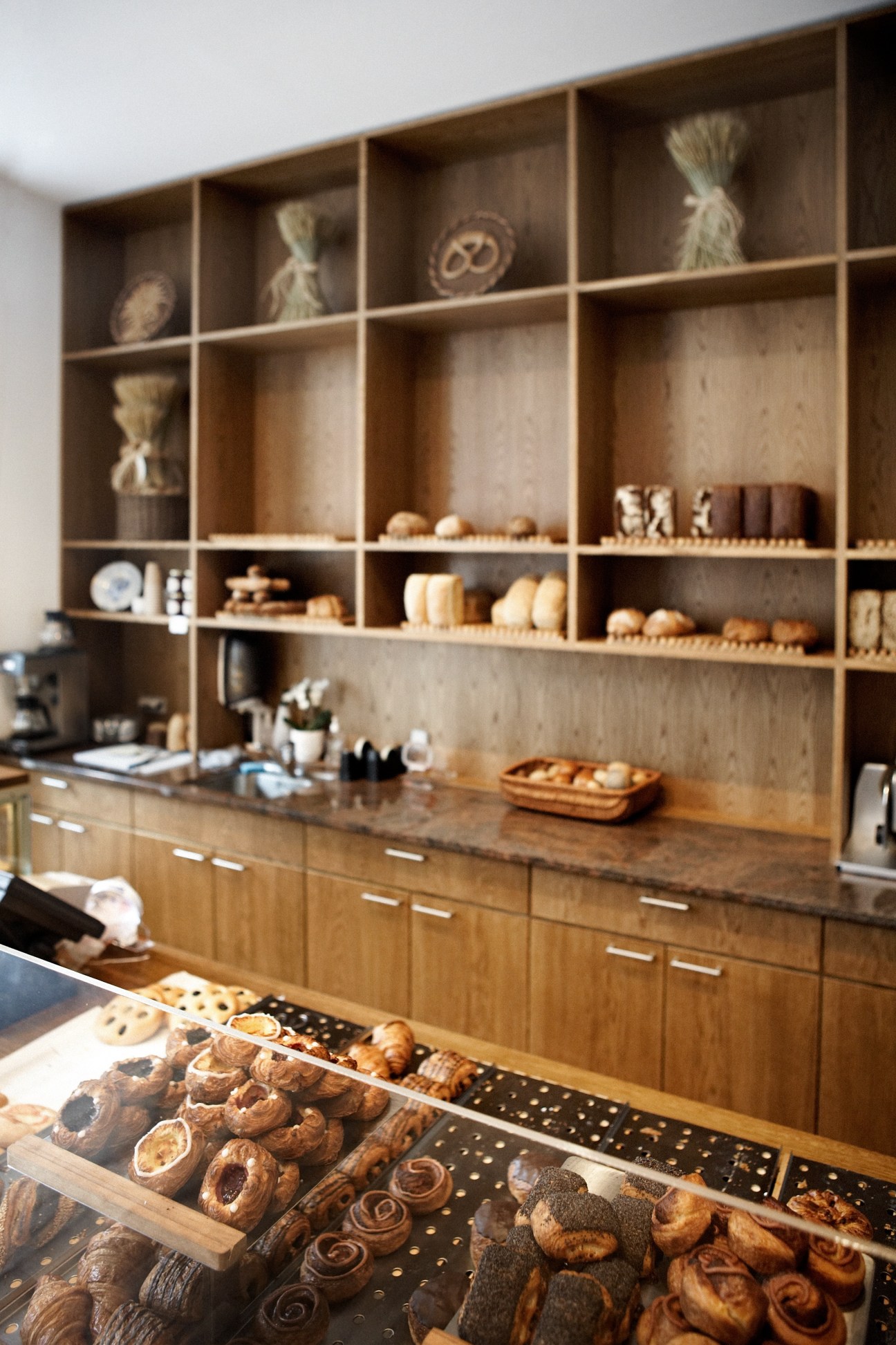 Interior of Andersen bakery in Copenhagen with wooden shelving, display cases of pastries and bread, and minimalist Scandinavian décor.