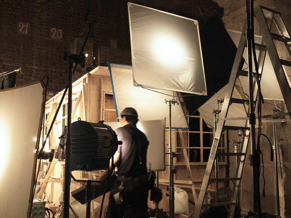 Film crew setting up lighting equipment and constructing a 1940s doctor's surgery set inside a barn for the Mexican film Tequila.
