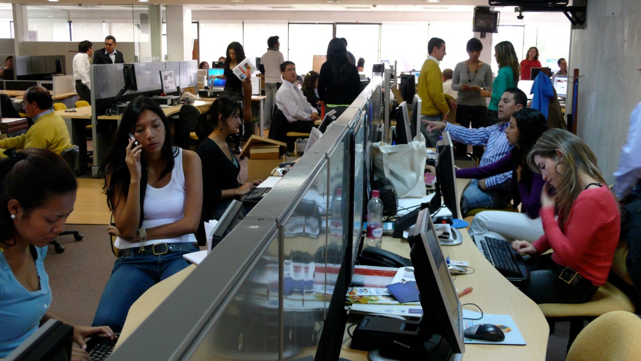 El Espectador newsroom with staff at desks working with computers and documents.